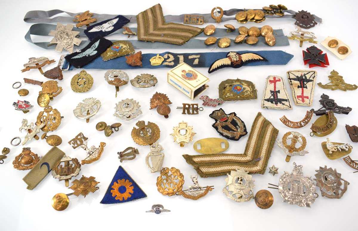 A collection of military cap badges, buttons, shoulder patches, match cover etc.