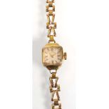 A ladies 9ct yellow gold wristwatch by Huguenin, the square dial with gold coloured baton numerals