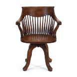 An early 20th century oak desk chair with a shaped seat and swivel base