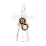 A yellow metal crossover ring set grey and white pearl within a border of small diamonds,ring size K