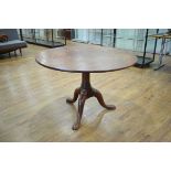 An 18th century mahogany tilt-top supper table, the circular surface on a turned column and three