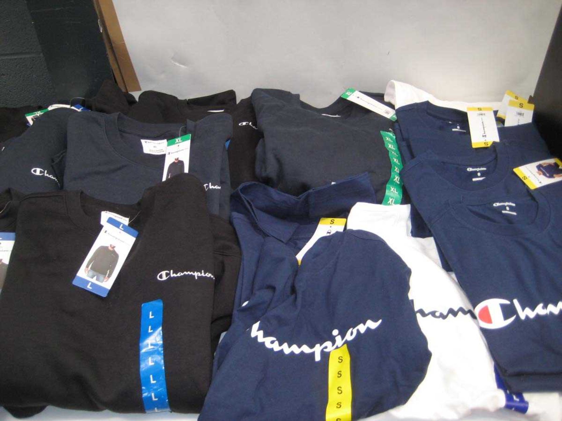 +VAT A bag containing 7x Men's Champion Sweatshirts in Navy & Black & 12x Champion T Shirts in