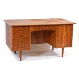 A 1960's Danish teak and crossbanded desk with an arrangement of five drawers and a door, on