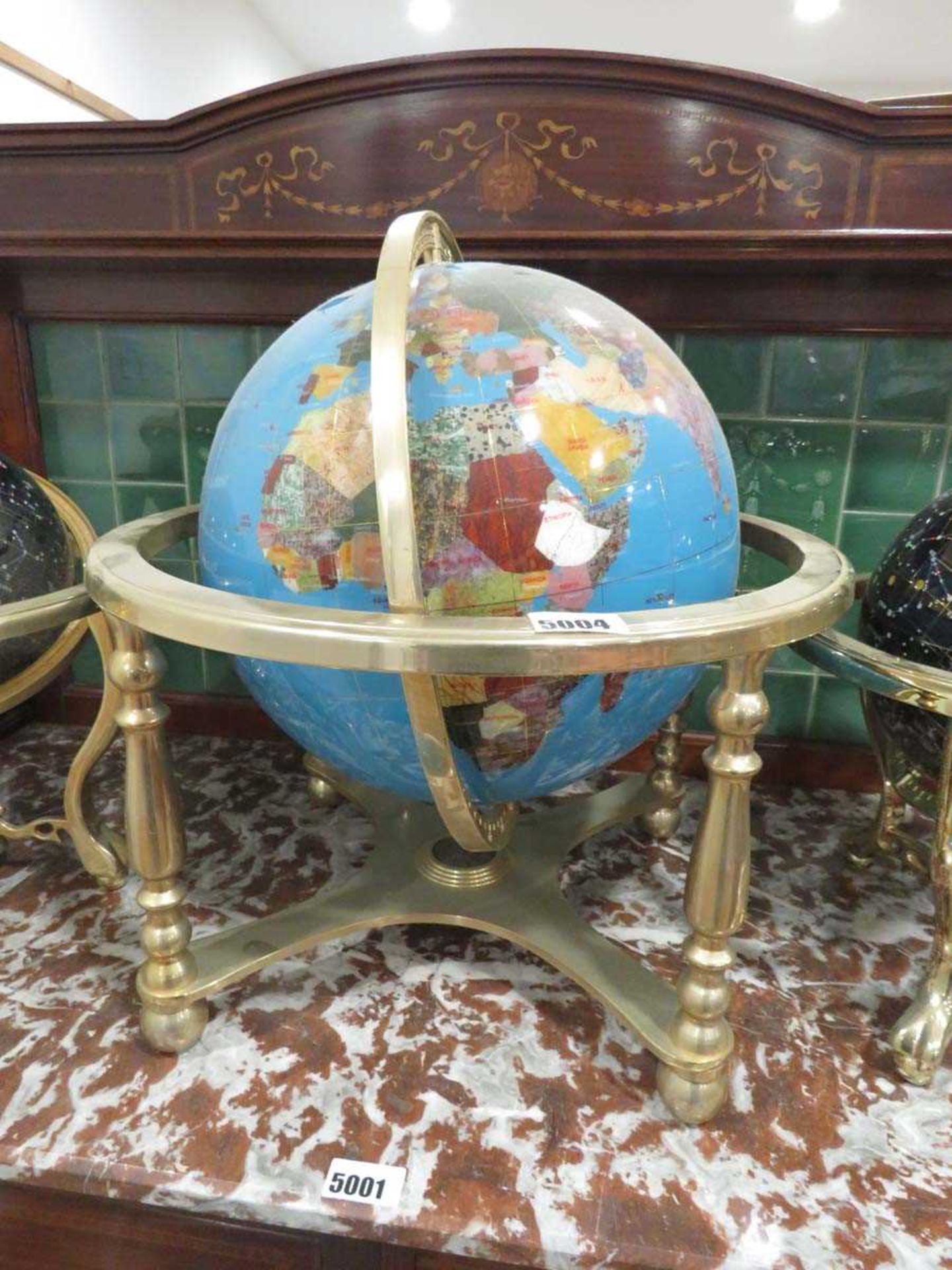 Small gem set globe contained within a brass stand
