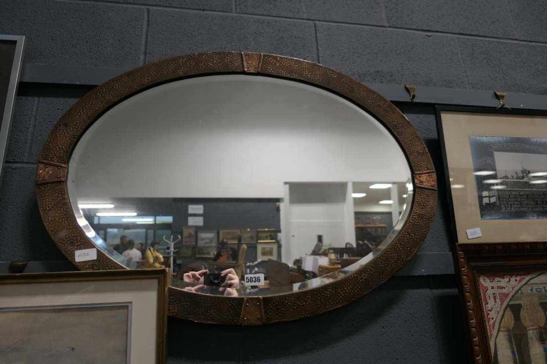 Arts and Crafts oval bevelled mirror in a beaten copper frame