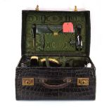 A vintage crocodile skin suitcase with a watered silk interior and various silver-mounted and faux