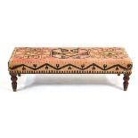 A rectangular stool covered in a Persian kilim, 124 x 48 cm