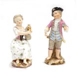 A pair of figures modelled as a dandy and his companion, each bearing faux Meissen crossed swords,