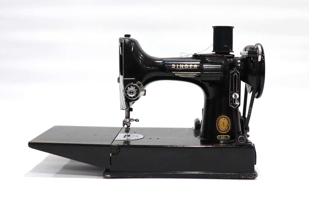 A cased Singer 221 featherweight free-arm sewing machineThere is a foot pedal, 3 spools and some