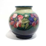 A Moorcroft bowl by Walter Moorcroft decorated in the 'Anemone' pattern on a green ground, h. 28