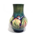 A Moorcroft vase by William Moorcroft decorated in the 'Leaf and Berry' pattern on a green ground,