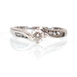 An 18ct white gold crossover ring set brilliant cut diamond in a raised four claw setting, the