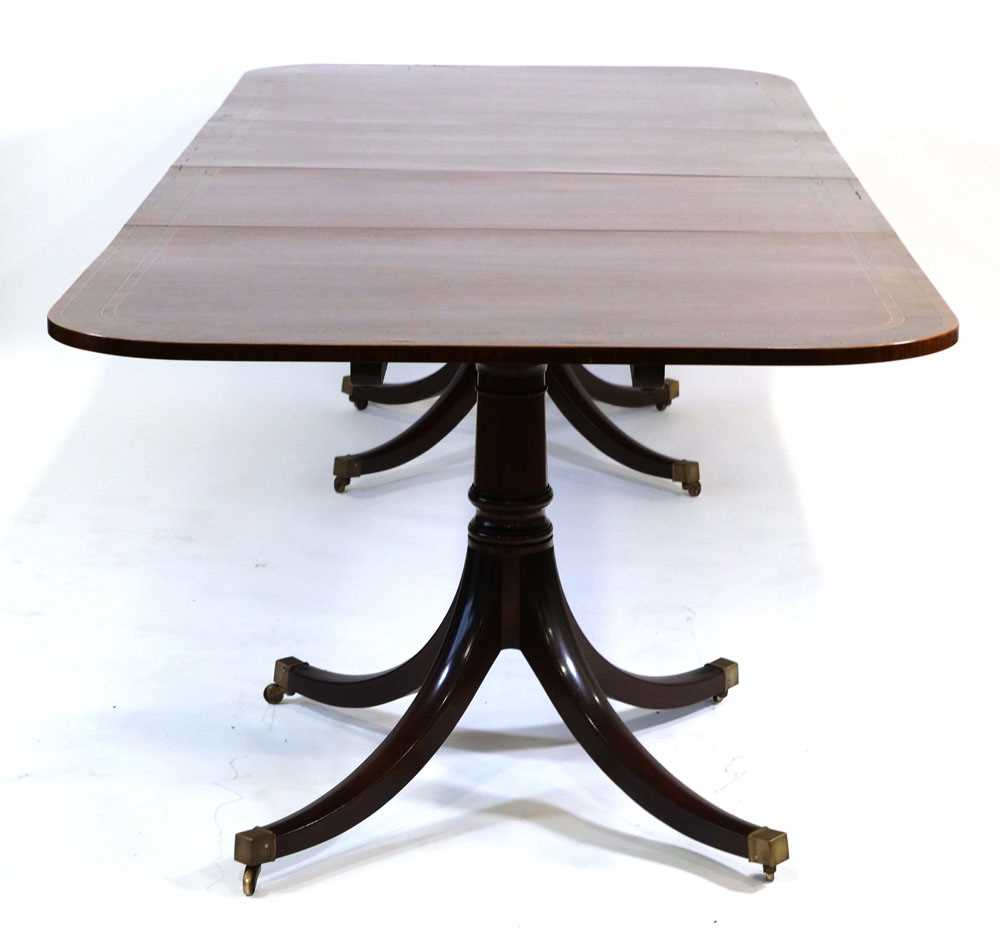 A Georgian-style mahogany, strung and walnut crossbanded twin-pedestal dining table with two