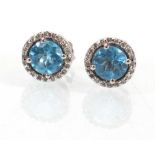 A pair of 18ct white gold ear studs, each set a pale blue stone cluster within a border of small