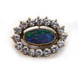 A yellow metal brooch set marquise shaped opal slither within a border of sixteen clear paste, w.