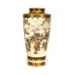 A Meiji period satsuma vase of slender baluster form profusely decorated with figures at leisure