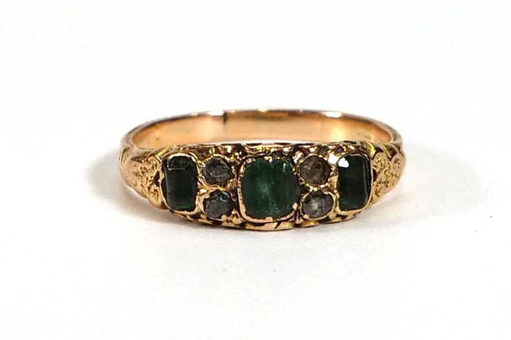 An early 20th century yellow metal ring set three square cut emeralds and three small diamonds in