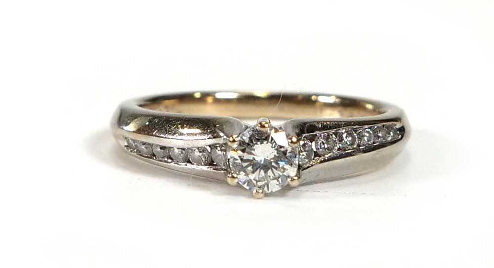 An 18ct white gold ring set brilliant cut diamond in a six claw setting, the shoulders each set