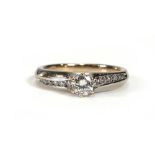 An 18ct white gold ring set brilliant cut diamond in a six claw setting, the shoulders each set