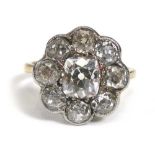 An early 20th century yellow metal ring set cushion cut diamond within a border of eight old cut