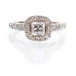 An 18ct white gold halo ring set princess cut diamond within a border of small brilliant cut