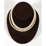 A three strand continuous cultured pearl necklace with 9ct yellow gold clasp set amethyst, l. 37 cm