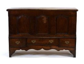 An 18th century oak mule chest, the chamfered surface over three front panels, three drawers and a