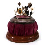 An Edwardian silver mounted pin cushion containing a selection of stick pins including a 15ct yellow