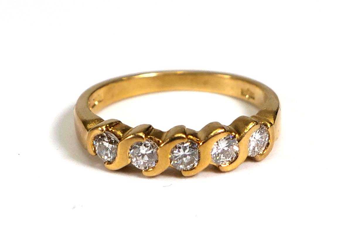 An 18ct yellow gold ring set five brilliant cut diamonds in s-shaped rubover settings,total