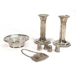 A group of silver comprising a pair of dwarf candlesticks, a stamped dish, a decanter label and