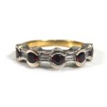 A yellow metal ring set five brilliant cut rubies interspersed with four baguette cut diamonds in an