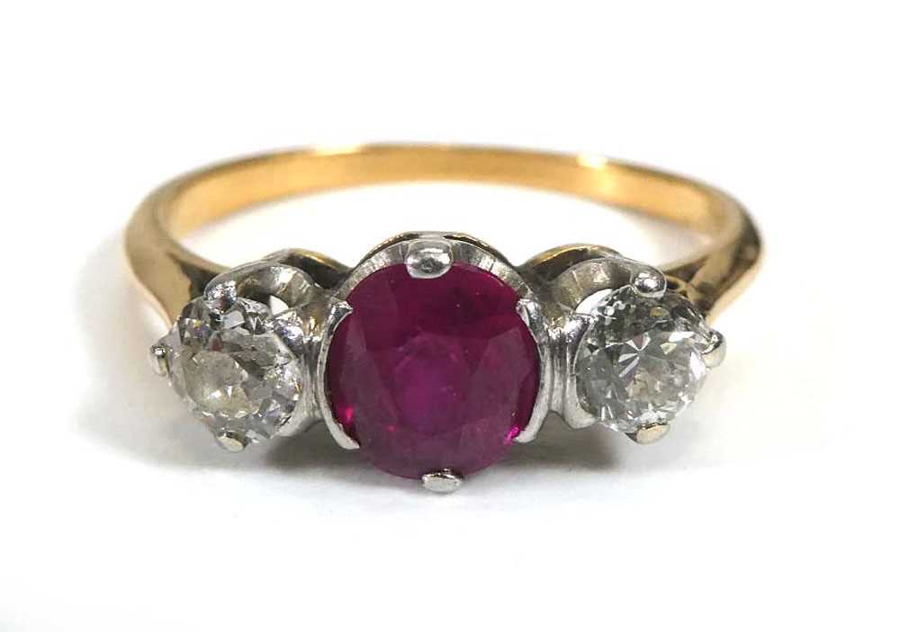 A yellow metal ring set round cut ruby and two old brilliant cut diamonds in an inline setting,