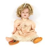 A composition Shirley Temple doll, with sleeping eyes and open mouth, wearing a badge and polka