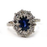 A white metal cluster ring set oval pale blue sapphire within a border of ten brilliant cut