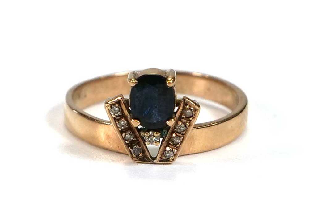 A yellow metal ring set oval sapphire and nine small diamonds in a coronet style setting, ring