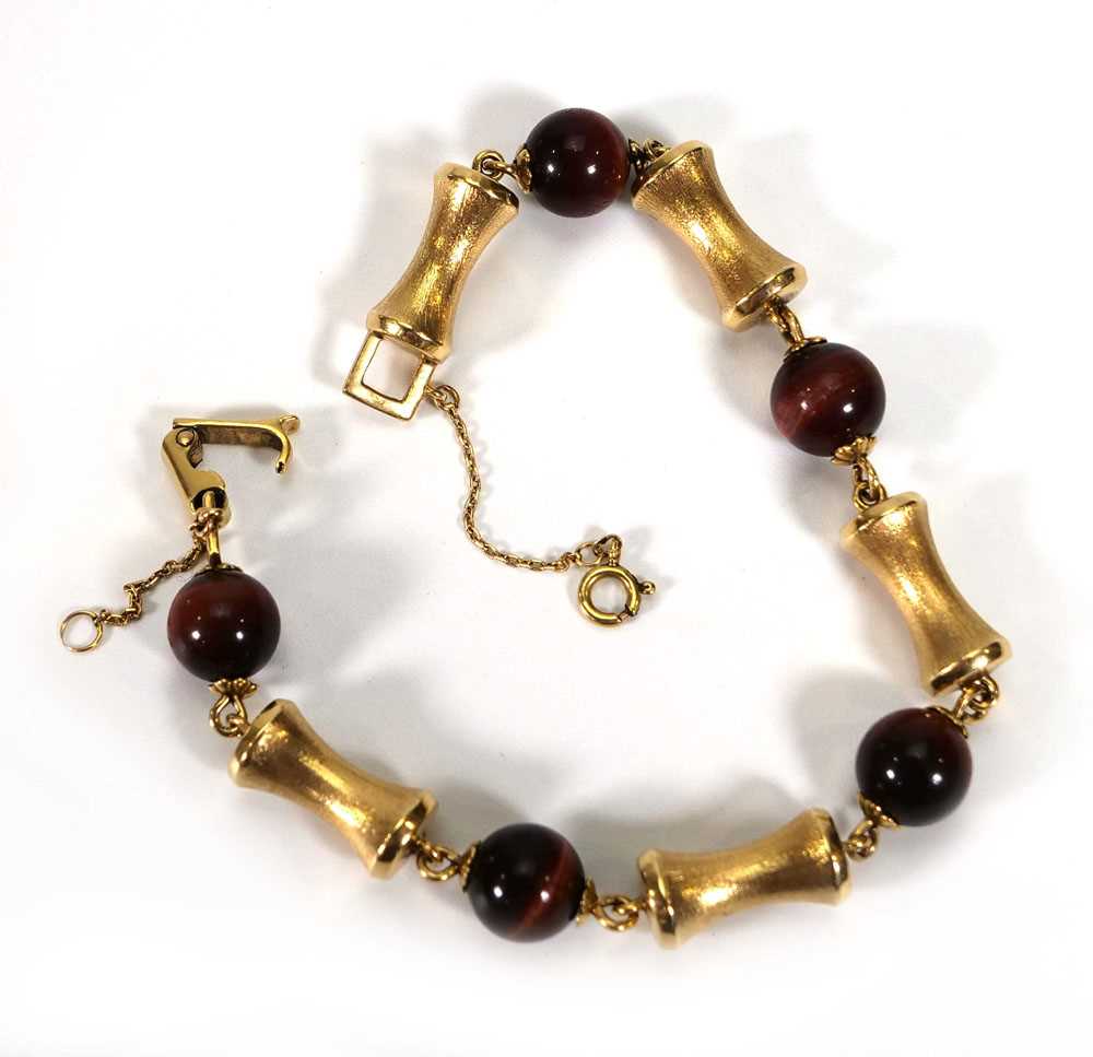 A yellow metal vertebrae and red tigers eye link bracelet, l. 20 cm, 23.4 gmsHallmarks indistinct