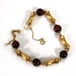 A yellow metal vertebrae and red tigers eye link bracelet, l. 20 cm, 23.4 gmsHallmarks indistinct