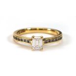 An 18ct yellow gold ring set emerald cut diamond in a four claw setting, the shoulders each set