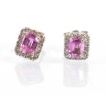 A pair of 18ct white gold ear studs, each set an emerald cut (?)pink sapphire within a border of