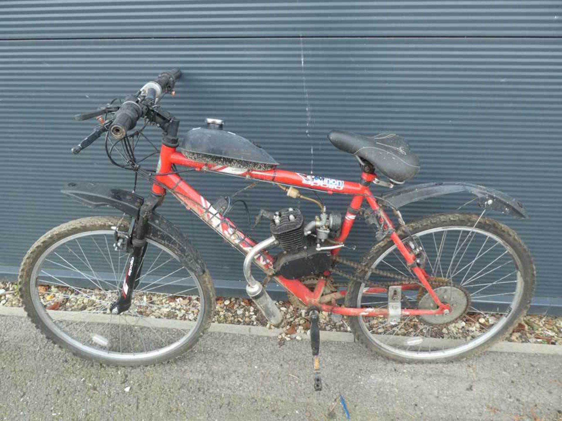 Red mountain bike with small petrol powered motor fitted