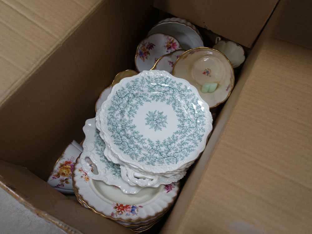 Box containing floral and leaf patterned crockery