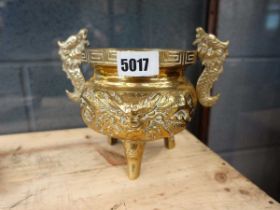 A Chinese brass censer relief decorated with a mask below a pair of applied handles, on three