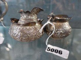 An Anglo-Indian metalware sugar bowl and two cream jugs, each repousse decorated with traditional