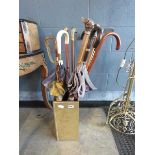 A brass finished stand with a quantity of umbrellas, walking sticks, golf club etc.