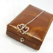 A 9ct white and rose gold entwined hearts pendant set with 0.23 carats of diamonds, boxed