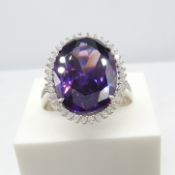 A large, striking silver cocktail ring set with purple and white cubic zirconia
