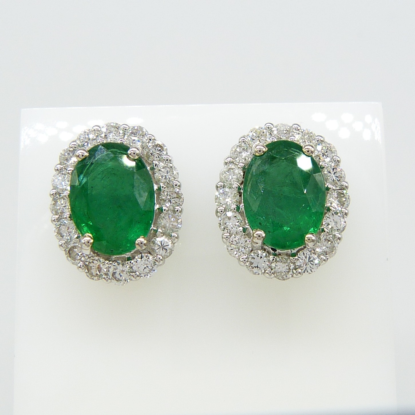 Pair of 18ct white gold 2.48 carat emerald and diamond halo ear studs, boxed
