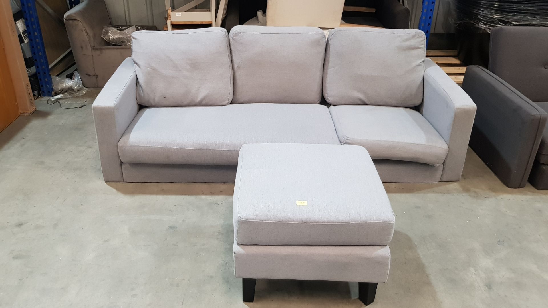 (87) 3 Seater Sofa Grey With Matching Foot Stool. (Please Note There Are No Legs In Lot).