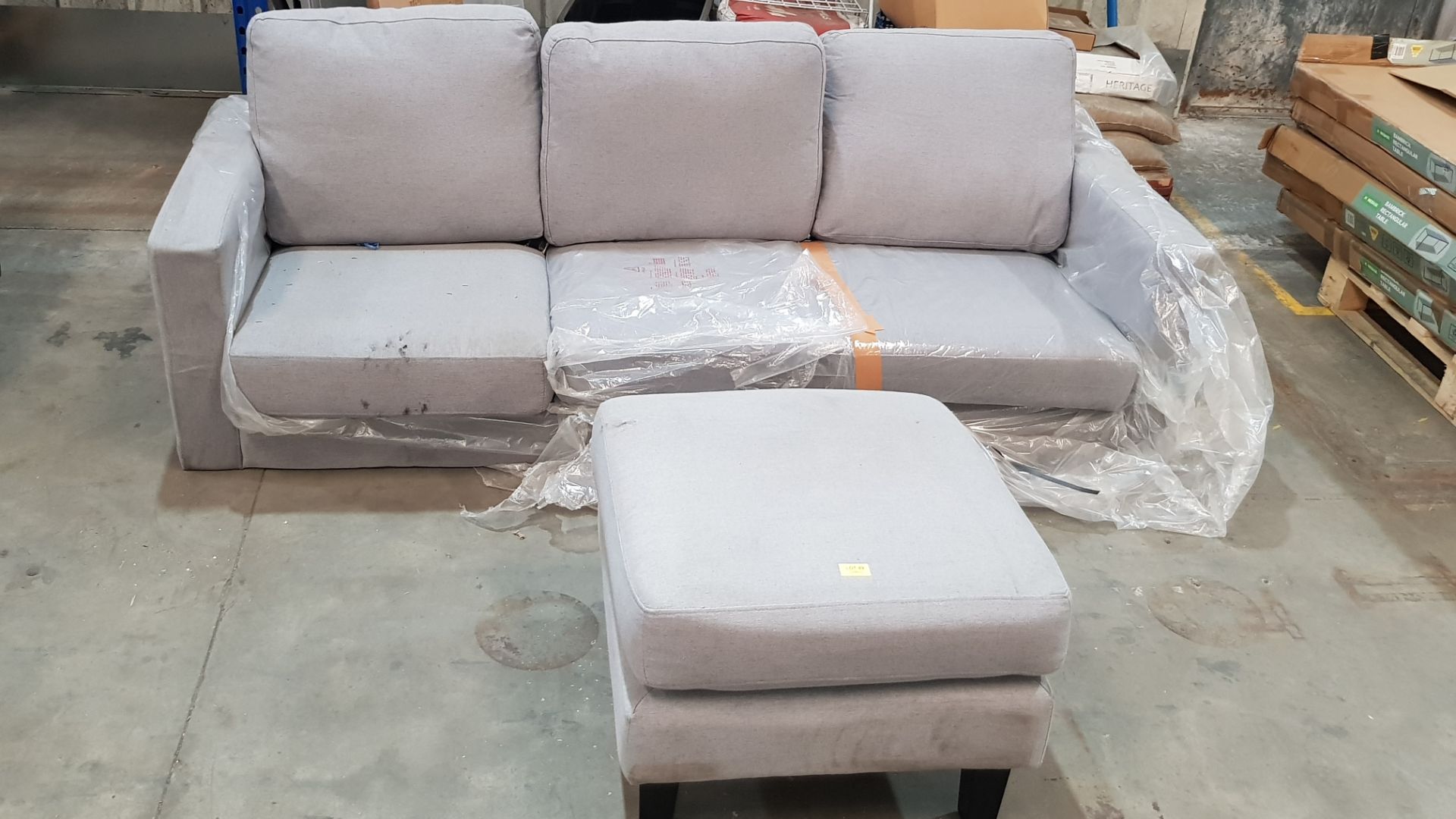 (89) 3 Seater Sofa Grey With Matching Foot Stool. (Please Note There Are No Legs In Lot).