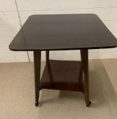 A Mid Century side table on tapering legs terminating on castors and swirl top